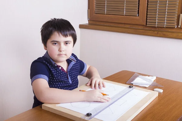 Poważny chłopak jest siedzi przy stole i zaangażowany przez rysunek — Zdjęcie stockowe