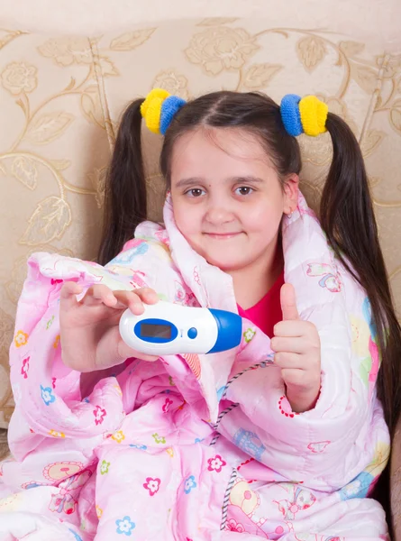 Vrolijk meisje gewikkeld in een deken en thermometer shows — Stockfoto
