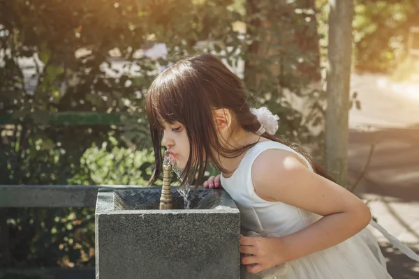 Kleines Mädchen trinkt Wasser aus einem Trinkbrunnen — Stockfoto