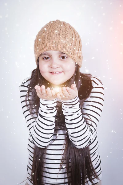 Fille avec les cheveux longs dans un bonnet de tricot beige tenant un scintillement dans ses mains — Photo