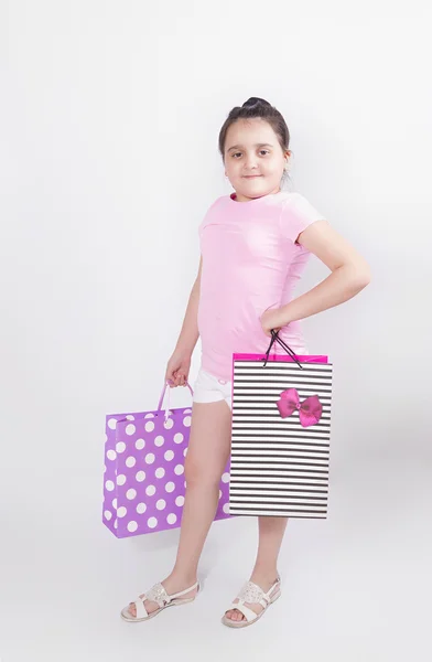 Chica con bolsas de papel de colores sobre un fondo gris —  Fotos de Stock