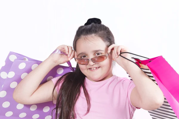 Vrolijk meisje in zonnebril met heldere papieren zakken — Stockfoto