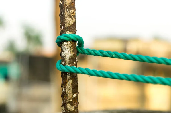 A rope is tied in a knot around a fence post, rope tied Hitch Knots on a rusty iron pole isolated from background.