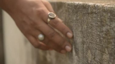 Yaz sabahı bir evin çatısındaki beton duvara hafifçe dokunan ve kayan bir kadın odak noktasından çıkar. Boşluğu kopyala.