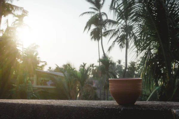 Coffee cup (Bhar) in sunset sunlight. Summer fresh cool look. Muddy mud tea cup made of clay for hot drink on roof beam of a residential building with bokeh city in the background. — Stock Image Coffee Cup Bhar Sunset Sunlight Summer Fresh Cool Look Muddy Stock Image