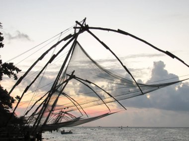 Tropik plajda gün batımı. Cochin 'de Çin balık ağları silueti olan okyanus manzarası. Kerala Güney Hindistan 'ın durgun suları
