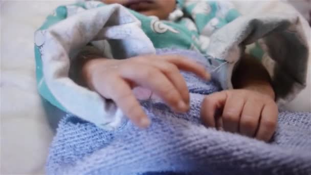 眠っている間に新生児が腕や足や指を動かす 閉めろ 美しい新生児の少年がベッドに横たわっている間病院病棟で赤ちゃん毛布に包まれて — ストック動画