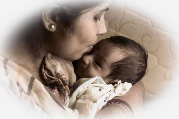 Close up face of a cute newborn baby boy kissed by her mother holding in her mother lap. One month old Sweet little infant toddler. Indian ethnicity. Front view. Happy mother day background image.