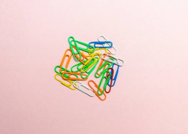 Ofis ataçları renkli arka planda izole edilmiş. Pembe, kırmızı, mavi, yeşil, turuncu renkli plastik ataç belge zımba aletleri.