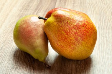 Sulu armutlara yakın çekim. Ahşap bir zeminde iki taze organik armut. Vejetaryen, vejetaryen sağlıklı yiyecekler. Diyet organik ürün. Seçici yumuşak odaklanma. Sonbahar hasadı.