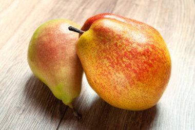 İki armuta yakın çekim. Ahşap bir zeminde iki taze organik armut. Vejetaryen, vejetaryen sağlıklı yiyecekler. Diyet organik ürün. Seçici yumuşak odaklanma. Sonbahar hasadı.