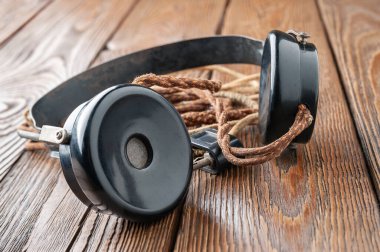 Eski kulaklıklar. Ahşap arka planda kumaş telli klasik kulaklıklar. Eski radyo mühendisliği kavramı. Seçici yumuşak odak.