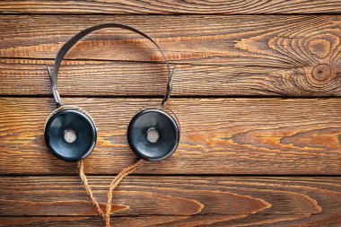 Eski kulaklıklar. Eski radyo kulaklıklarının ahşap arka planda kabloları var. Kopya uzayı ile ilgili eski bir radyo mühendisliği kavramı. Seçici yumuşak odak.