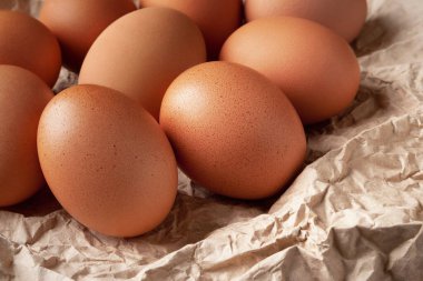 Tavuk yumurtası. Buruşuk ambalaj kağıdındaki çiğ kahverengi yumurtalar kırsal bir tarzda. Yüksek kalorili protein konsepti. Seçici yumuşak odak.