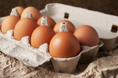 Yumurta kutusundaki tavuk yumurtaları. Buruşmuş ambalaj kağıdına çiğ kahverengi tavuk yumurtası. Yüksek kalorili protein konsepti. Seçici yumuşak odak.