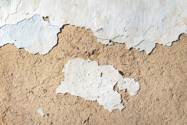 The old plastered wall background. The texture of the old peeling cracked, weathered plaster with chips and cracks. Collapsing clay wall. Destructive influence of time, environment. Texture background