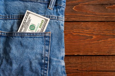 Para cepte. Ahşap bir arka planda kot pantolon cebinde 100 Amerikan doları. Uzayı kopyala Para kazanma ve biriktirme kavramı. Amerikan parası 