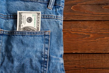 Para cepte. Ahşap bir arka planda kot pantolon cebinde 100 Amerikan doları banknot. Uzayı kopyala Para kazanma ve biriktirme kavramı. Amerikan parası