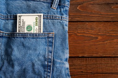 Para cepte. Tahta bir arka planda kot pantolon cebinde 100 Amerikan doları banknot. Uzayı kopyala Para kazanma ve biriktirme kavramı. Amerikan parası