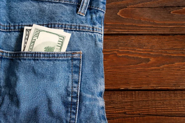 钱在口袋里牛仔裤口袋里的美元钞票在木制底座上 复制空间 赚钱和省钱的概念 美国货币 — 图库照片