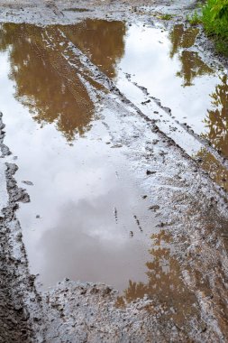 Gölet off-road 'da. Kirli toprak yol ve su birikintisindeki yansıma. Lastik izleri. Çamurlu bir yolda Rut. Çamurdaki tekerlek izleri. Kötü hava.