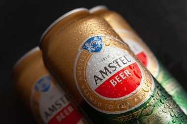 Su damlalı bira kutuları. Islak siyah arka planda ıslak kutularda AMSTEL birası. Hollanda 'dan dünyaca ünlü bir marka. Seçici yumuşak odaklanma. Kiev. Ukrayna. Haziran-26.2021.