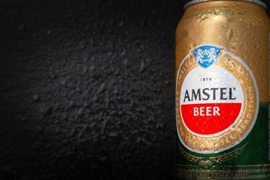 Su damlalı bira kutusu. Islak kutuda AMSTEL birası, yakın plan logo. Dünyaca ünlü Hollanda markası. Fotokopi alanı olan siyah ıslak arka plan. Seçici yumuşak odaklanma. Kiev. Ukrayna. Haziran-26.2021.