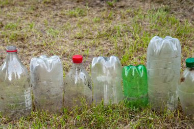 Plastik şişeler. Kurumuş çimenlerin üzerinde kullanılmış eski, kirli plastik şişeler. Çevre kirliliği kavramı. Ekolojik bir sorun. Plastik atıkların geri dönüşümü. Seçici yumuşak odak.