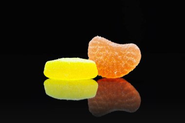 Jöleli şekerler. Siyah arka planda sarı ve turuncu narenciye reçeli.