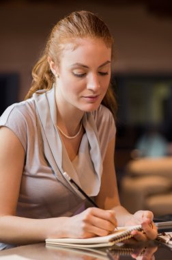 Woman writing on block notes