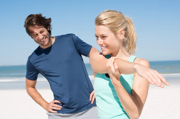 Paar dehnt sich am Strand — Stockfoto