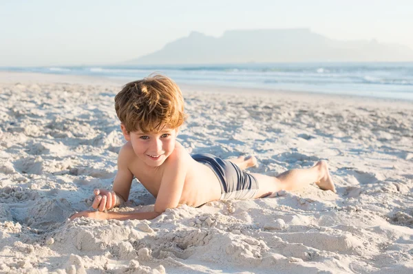 Kleine jongen liggen op strand — Stockfoto