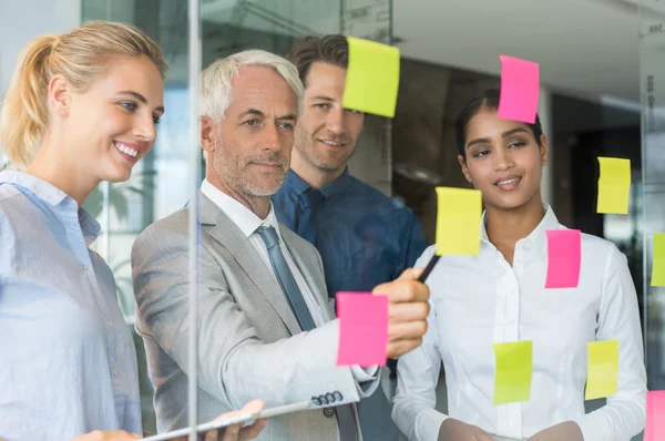 Equipo de negocios mirando notas adhesivas — Foto de Stock