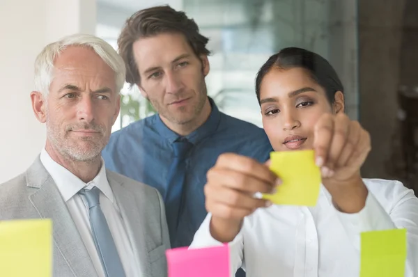 Empresaria pegando notas adhesivas — Foto de Stock