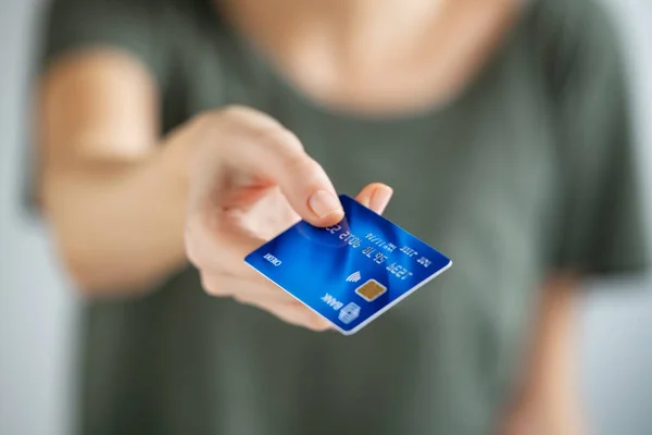 若い女性の手のクレジットカードを保持を閉じます 女性はレジ係にクレジットカードを与えるために手を伸ばす 青いクレジットカードで支払う女の子の終わり — ストック写真