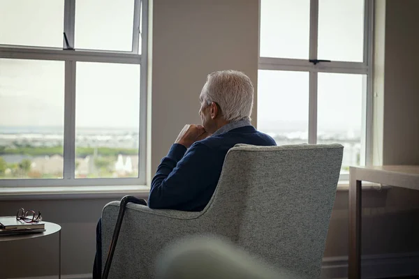 老年人坐在扶手椅上从窗户往外看的后视镜 在危机爆发期间 孤独的老人坐在窗边的家中 手里拿着手杖 被抛弃在疗养院的有识之士 — 图库照片