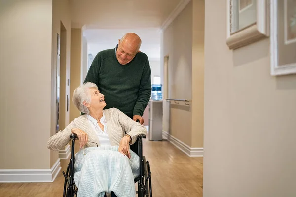 Yaşlı Adam Hastane Koridorunda Tekerlekli Sandalyedeki Engelli Karısını Itiyor Mutlu — Stok fotoğraf