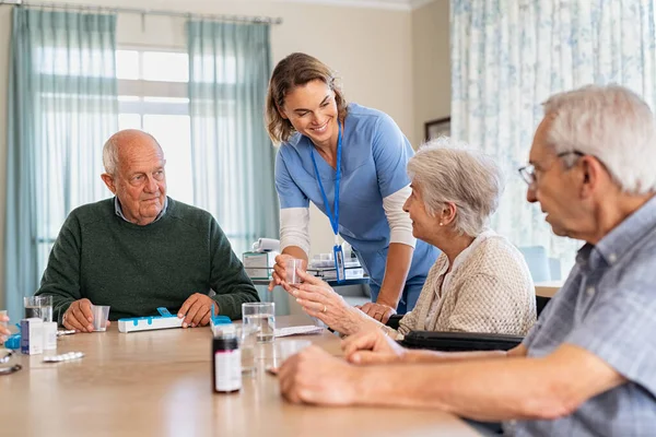 Ung Sjuksköterska Uniform Som Ger Medicin Till Pensionärsgrupper Glad Leende — Stockfoto