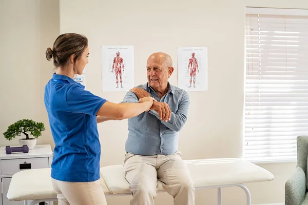 Fiatal Fizioterapeuta Segít Időseknek Könyök Gyakorlásban Klinikán Fiatal Kiropraktikus Ellenőrző — Stock Fotó