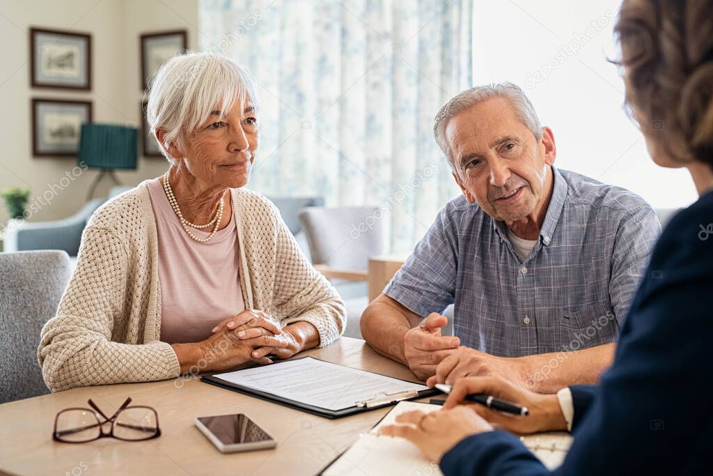 Senior man and woman meeting medical adviser for health insurance at home. Old couple planning their investments with financial advisor after retirement at home. Aged couple consulting with insurance agent while sitting together with prospectus at ho