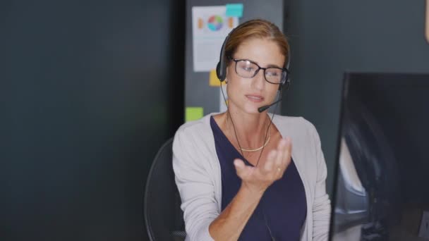 自宅から仕事をしながらキーボードを入力してヘッドフォンで焦点を当てたビジネスウーマン ビデオ通話中に自宅でコンピュータを使用してヘッドセットを使用してストレス成熟した女性 — ストック動画