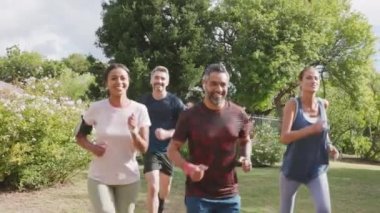 Çok ırklı orta yaşlı erkek ve kadınlardan oluşan sağlıklı bir grup parkta koşuyor. Birlikte koşan mutlu melez çiftler. Olgun arkadaşlar birlikte dışarı koşarlar..
