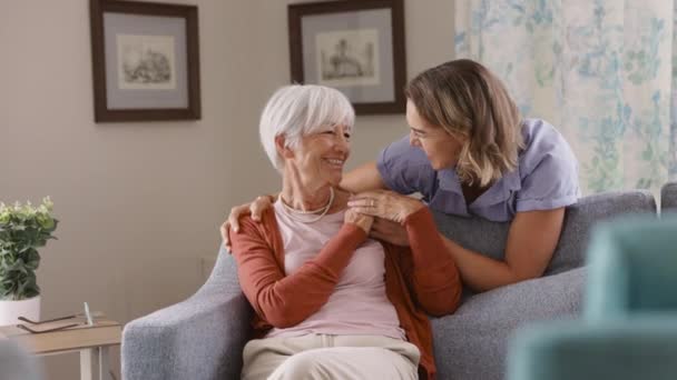 Smiling Adult Daughter Embracing Old Mother Sitting Sofa Laughing Together — Stock Video