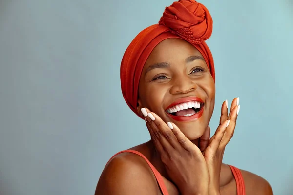 一个快乐的黑人成熟女人的画像 有着非洲式的发型 背景是蓝色的 她把目光移开 快乐的中年非洲女人在墙上孤零零地笑 无忧无虑的中年妇女享受并享受复印空间的乐趣 — 图库照片
