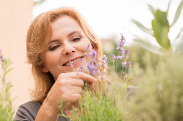 Mujer madura mirando flores — Foto de Stock