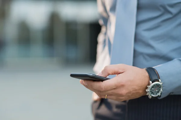 Empresário segurando smartphone — Fotografia de Stock