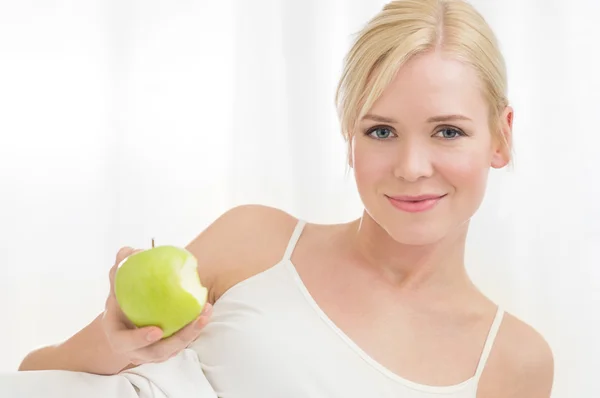 Молодая женщина ест зеленое яблоко — стоковое фото