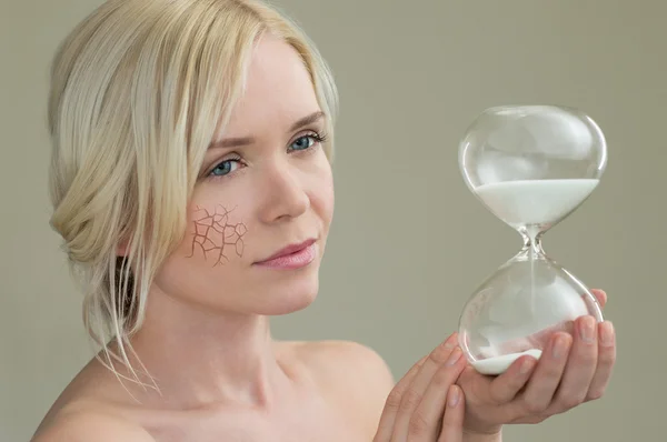 Mujer joven sosteniendo vidrio de hora — Foto de Stock