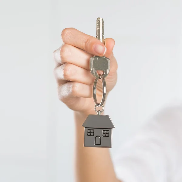 Mulher segurando chave com casa pequena — Fotografia de Stock