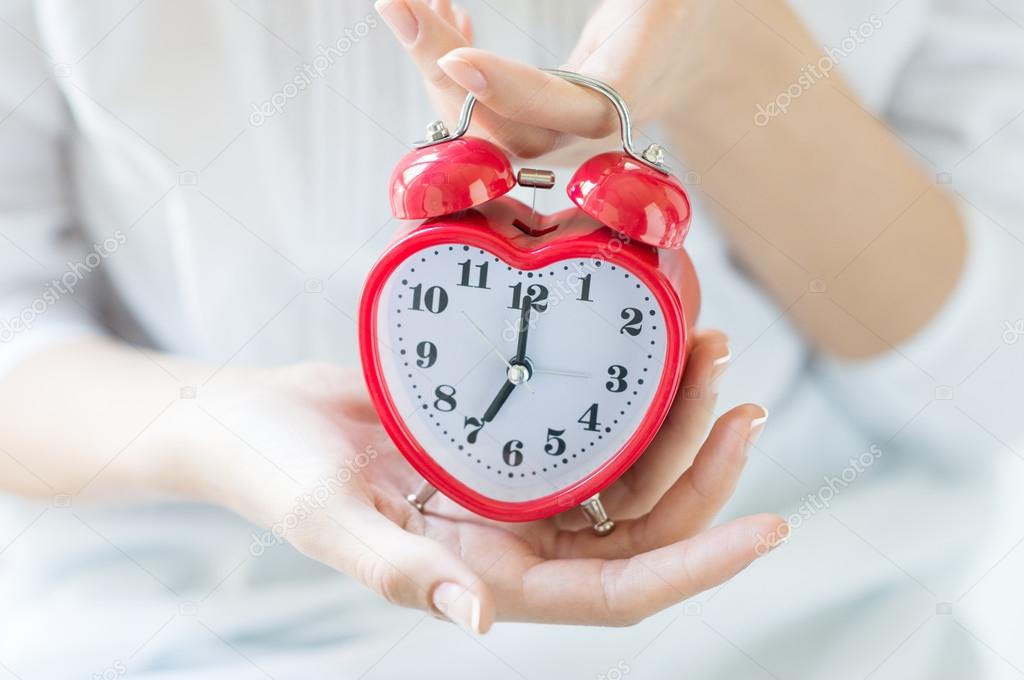 Woman hands holding alarm clock